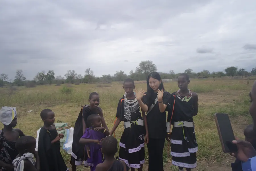 Korrine with Maasai girls in a grassy field