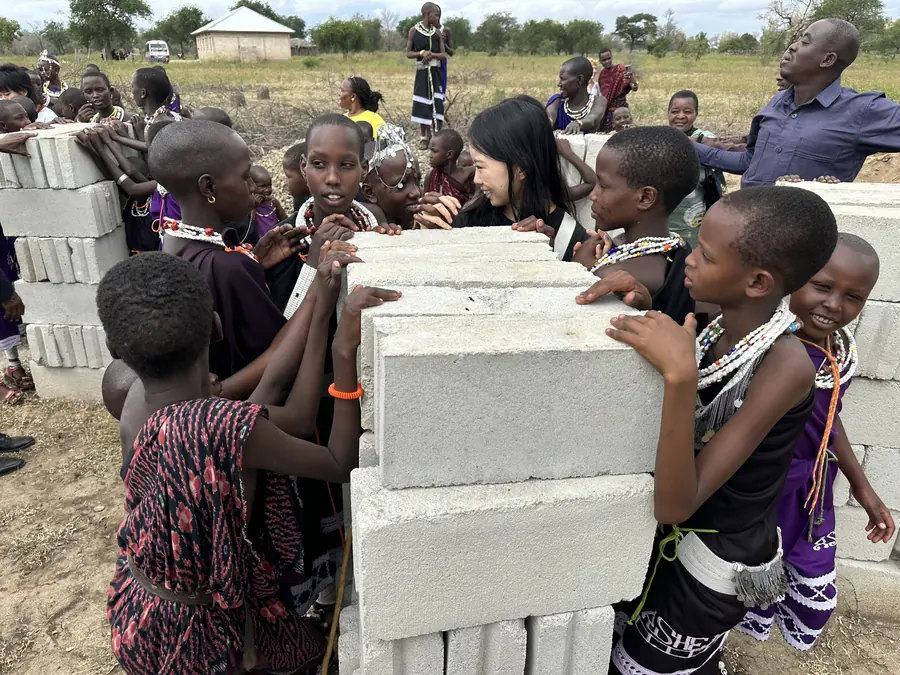 Maasai children leaning on a stack of cement blocks