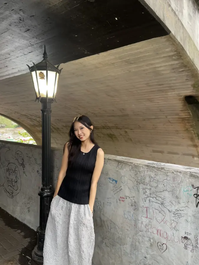 Korrine Lee standing beneath a stone bridge beside a lamppost