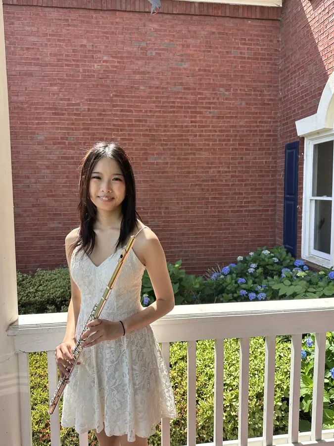 Korrine Lee in a white dress holding a flute on a porch